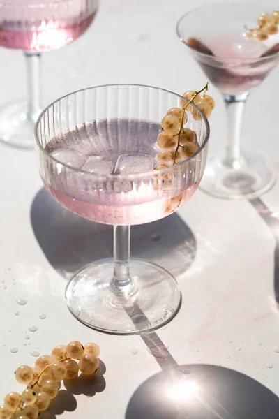 Fancy pink cocktails decorated with withe currants on pink white background-