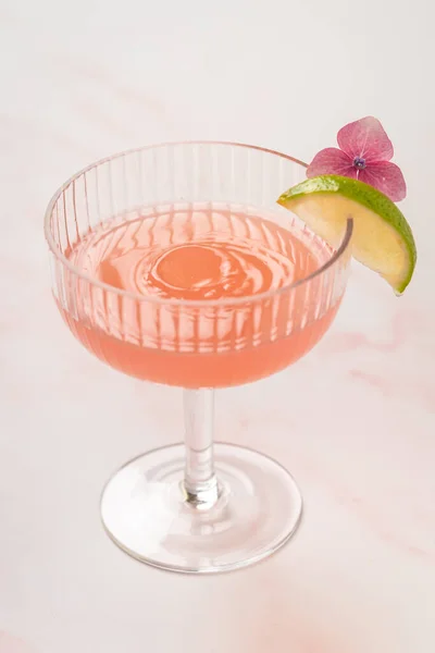 Różowy Napój Koktajlowy Kroplą Wody Szklance Ozdobiony Limonką Kwiatem — Zdjęcie stockowe