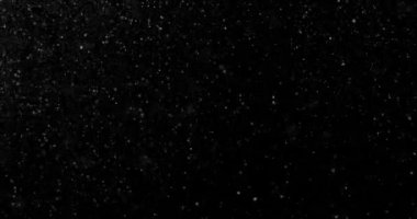 Siyah zemin üzerinde rastgele uçan küçük beyaz parçacıklara sahip video