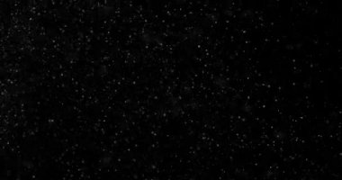 Siyah zemin üzerinde rastgele uçan küçük beyaz parçacıklara sahip video