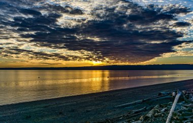 Burien, Washington 'da Puget Sound' da kara bulutlu bir gün batımı.