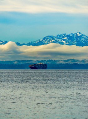 Bir gemi arkadaki Olumpic Dağları 'yla Puget Sound' u geçti..