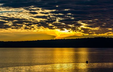 Burien, Washington 'da Puget Sound' da kara bulutlu bir gün batımı.