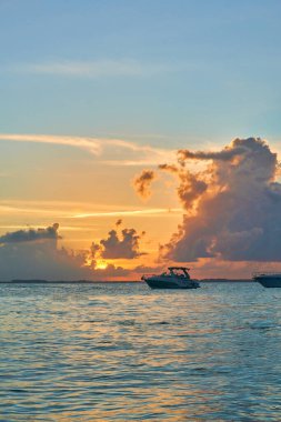Ada Mujeres 'in kuzey sahilinde gün batımında bir tekne. Bir sürü mavi ve turuncu bulutlu muhteşem bir gökyüzü..