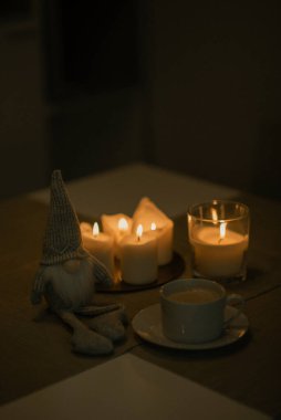 Masasında mumlar olan sevimli bir cüce ve bir lamba.