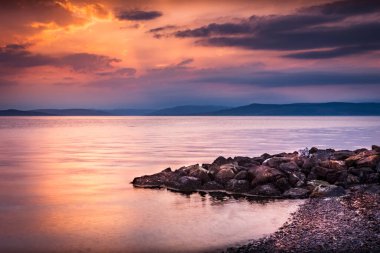 Wemyss Körfezi 'nde yansıtıcı sakin deniz manzaralı parlak turuncu gün batımı İskoçya, İngiltere' de kayalık kıyı şeridi.
