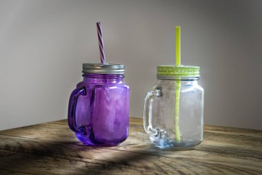 Beyaz arkaplan ve pipetli cam bardaklar ahşap masada oturuyordu..