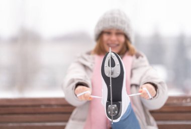 Bir kız parkta bankta otururken patenlerini bağlar. Genç bir kadın paten sahasına geldi..