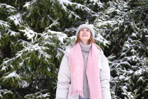 少女は雪を楽しんでいます ガーランドと緑のクリスマスツリーのそばに立って 雪に覆われた森の中の若い女性の冬の写真 — ストック写真
