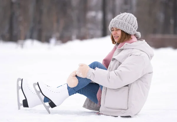 少女は冬にアイスリンクに落ちた 秋の後 若い女性がスケートで氷の上に座っている — ストック写真