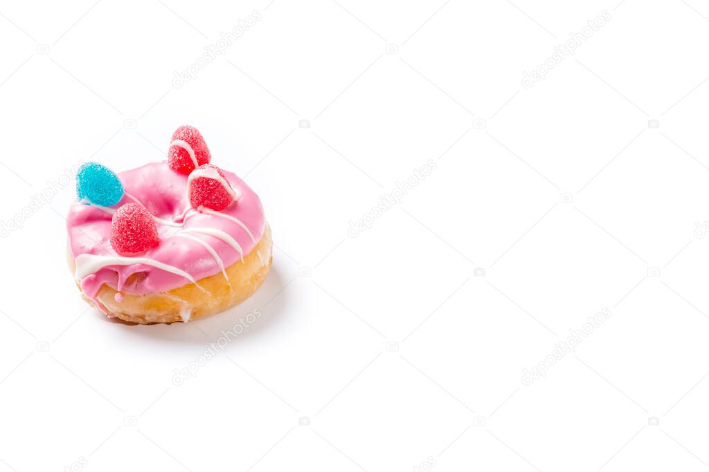 Photograph of a pink donuts painted with white chocolate and decorated with jelly beans.The photo is taken in horizontal format on a white background and has copy space.