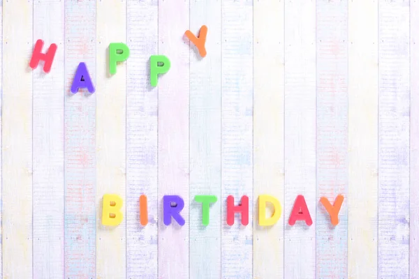 Photograph of some magnet letters with the English text of Happy Birthday on a colored cardboard background.The photograph is taken in horizontal format and from an overhead point of view. — Stock Photo, Image