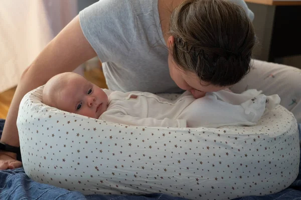 Anya szagolgatja a büdös pelenkát a kislányáról, ellenőrzi, hogy ideje-e kicserélni.. — Stock Fotó