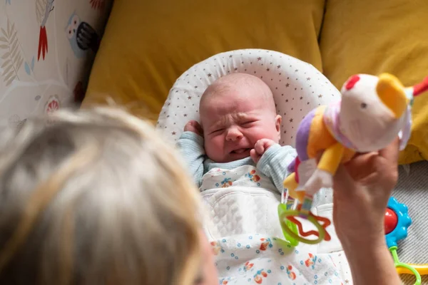 Caucasian two month baby on the bed looking on a beanbag toy crying — Stock Photo, Image