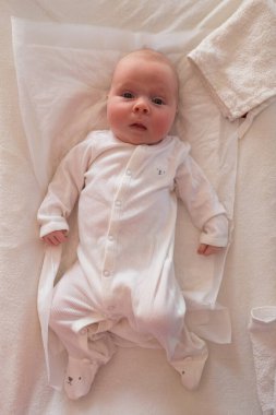 Bebek kız bebek masasında dinlenirken kameraya bakıyor.