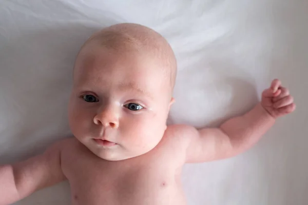 Niña mirando a la cámara descansando en el cambiador de bebé — Foto de Stock