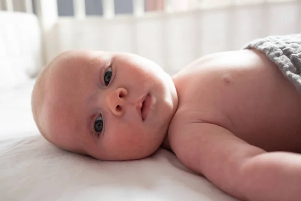 Baby girl looking at camera resting in baby changing table — Stock Photo, Image