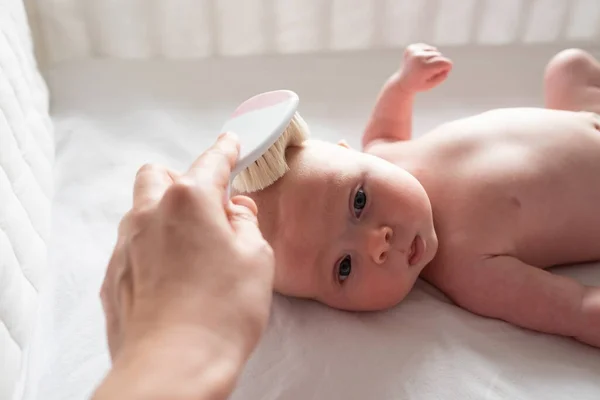Hairbrush and baby care. Mother combing newborn hair — Stock Photo, Image