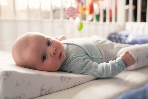 Cute baby girl looking at camera resting in bed — Stock Photo, Image