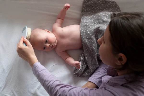 Cepillo y cuidado del bebé. Madre peinando el cabello recién nacido — Foto de Stock