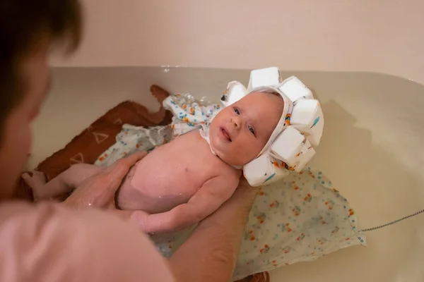 Baby having a bath wearing special swimming hat. — Stock Photo, Image
