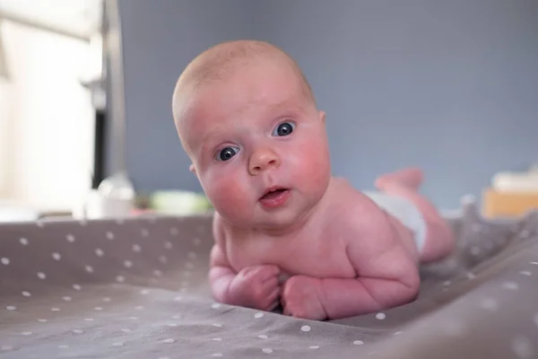 Bayi perempuan melihat kamera beristirahat di meja ganti bayi — Stok Foto