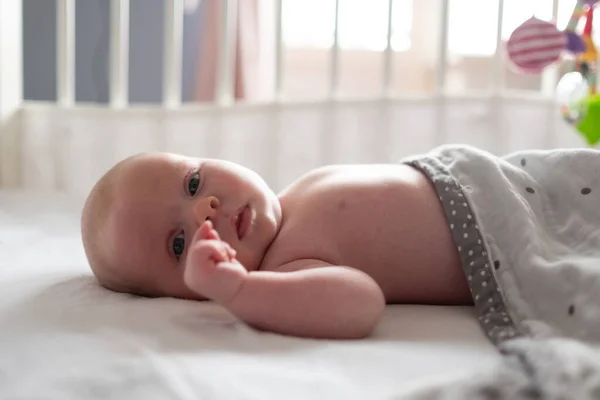 Baby girl looking at camera resting in baby changing table — Stock Photo, Image