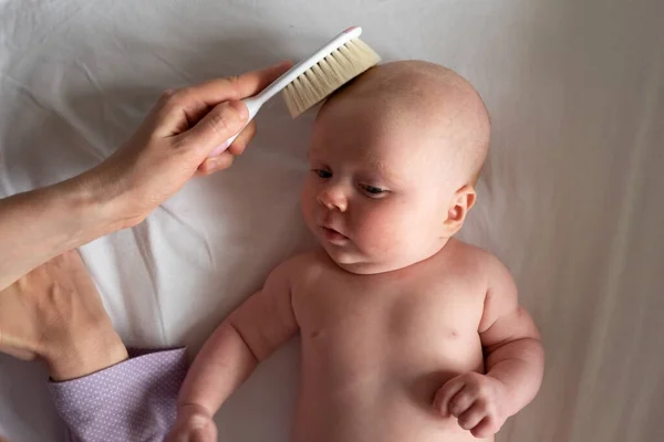 Cepillo y cuidado del bebé. Madre peinando el cabello recién nacido — Foto de Stock