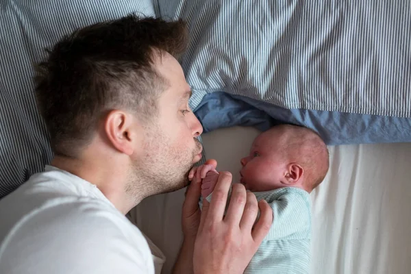 Молодий батько проводить час своєї новонародженої дівчинки в ліжку — стокове фото