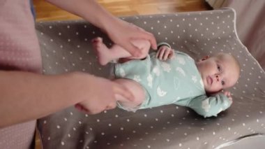 Anne bebek bacaklarına masaj yapıyor, kaslar için egzersiz yapıyor.