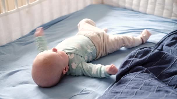 Ребенок просыпается утром, ожидая, когда его родители дернутся руками и ногами — стоковое видео