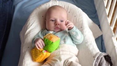 evde bir yatakta bir oyuncakla oynayan erkek bebek