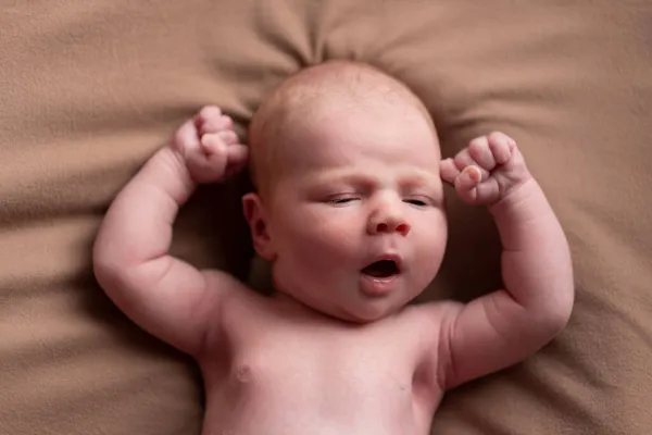 Yawning caucasian newborn baby yawning resting on brown blanket. — ストック写真