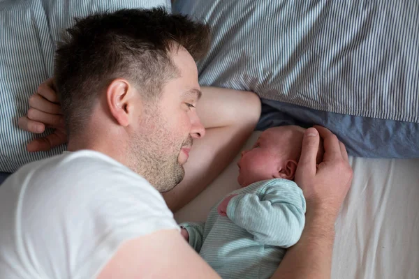 Ung far tillbringar tid med sin nyfödda flicka i sängen — Stockfoto