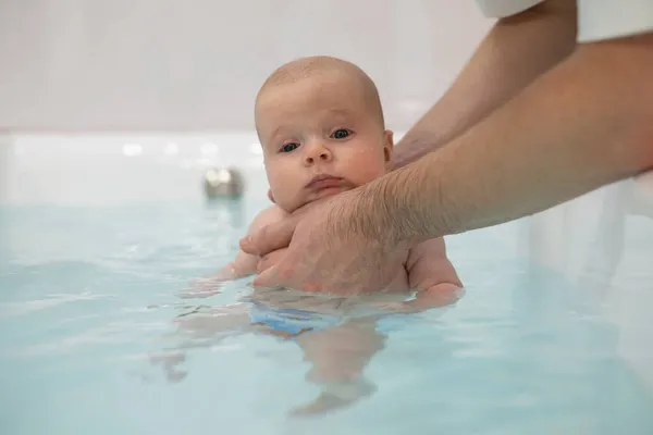 Caucasian 2 month baby exercising in swimming pool — Stock Photo, Image