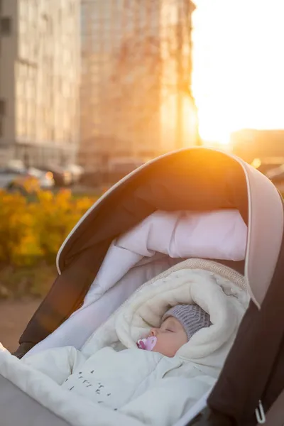 En liten pojke i barnvagn utomhus. Gul löv runt honom. — Stockfoto