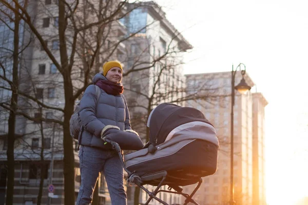 Happy young mother with pram during the walk — Stock Photo, Image