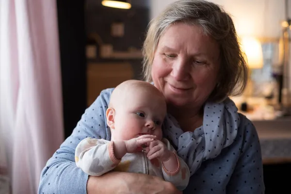 Літня жінка бабуся тримає новонародженого на руках — стокове фото