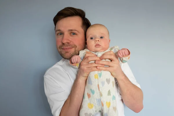 Young man holding a 3months old baby, isolated on blue background — Stock Photo, Image