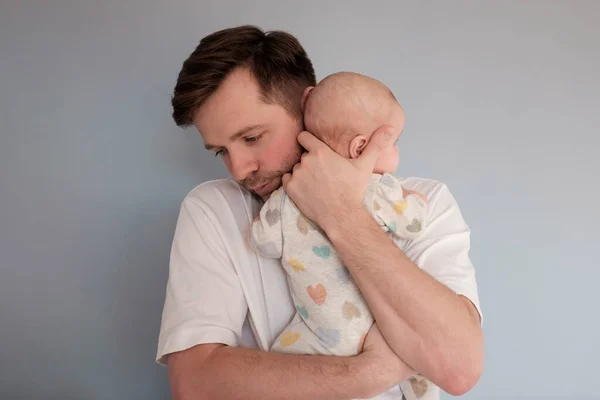 Triste jeune homme tenant un bébé de 2 mois, isolé sur fond bleu — Photo