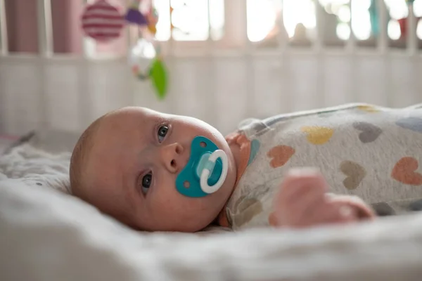 Cute little baby with pacifier resting in bed — Stock Photo, Image