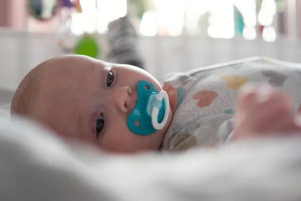 Cute little baby with pacifier resting in bed — Stock Photo, Image