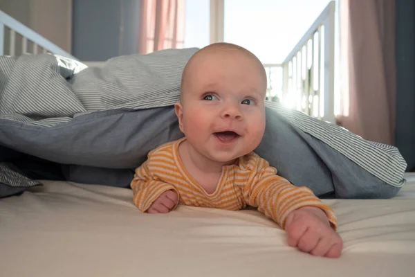 Funny caucasian baby lying on the bed. — Stock Photo, Image