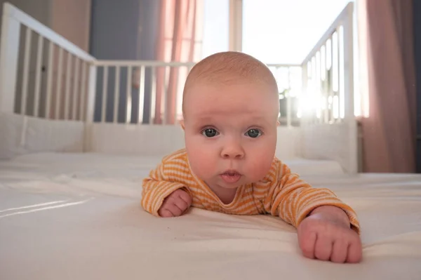 Engraçado bebê caucasiano deitado na cama. — Fotografia de Stock