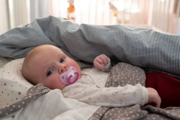 Baby girl with a soother on the bed at the mprning — Stock Photo, Image
