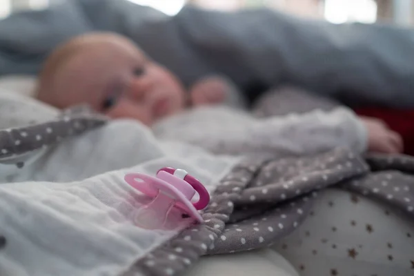 Baby meisje met een speentje op het bed bij de mprning — Stockfoto