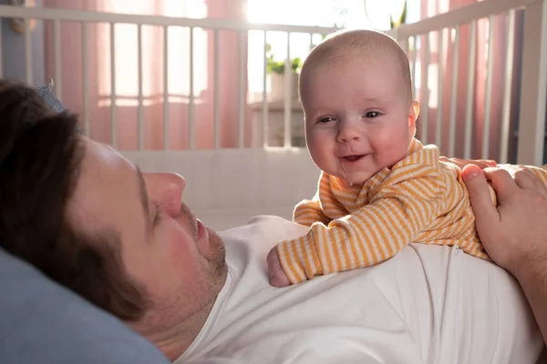 Genç baba yeni doğmuş bebeğini yatakta geçiriyor. — Stok fotoğraf