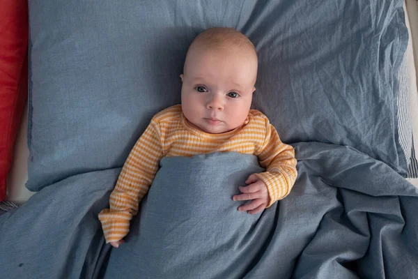 Funny caucasian baby lying on the bed. — Stock Photo, Image
