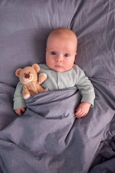 Funny caucasian baby lying on the bed. — Stock Photo, Image