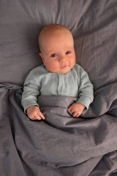 Divertido bebé caucásico acostado en la cama. — Foto de Stock